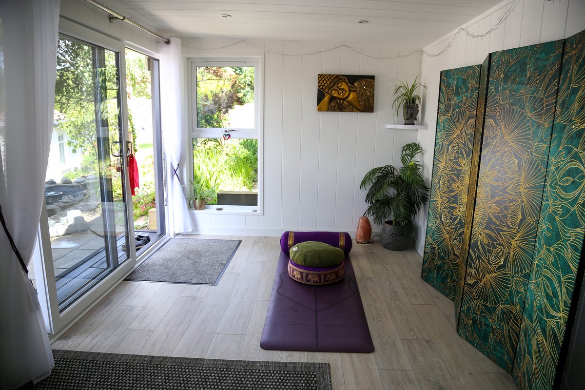 Inside the garden studio, with yoga mats laid out and the garden visible through the open doors